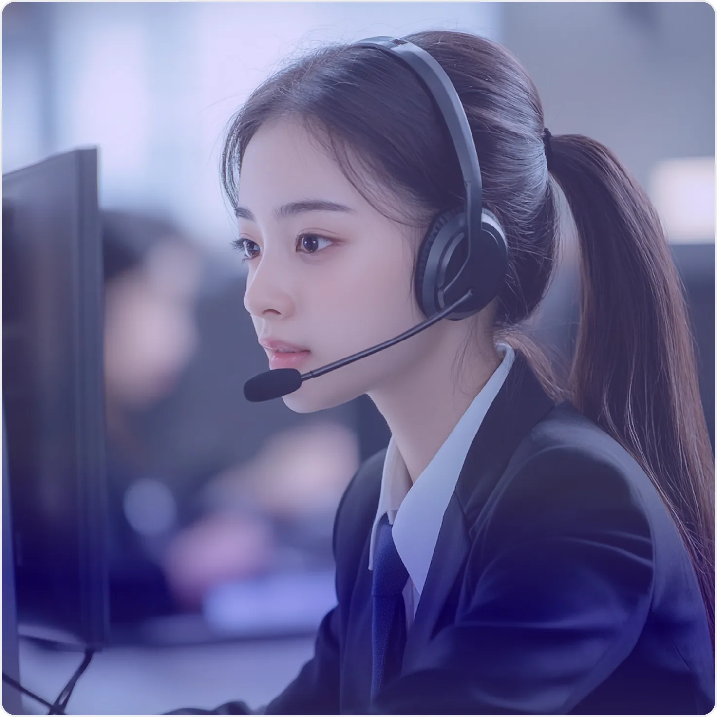 Young woman with headset working at a computer in a professional setting.